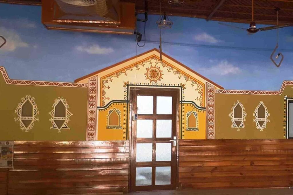 Vibrant Rajasthani hand-painted mural by ArtHerwa, showcasing a traditional Indian house with intricate windows and colorful walls—Mural Art Services in Gurgaon.